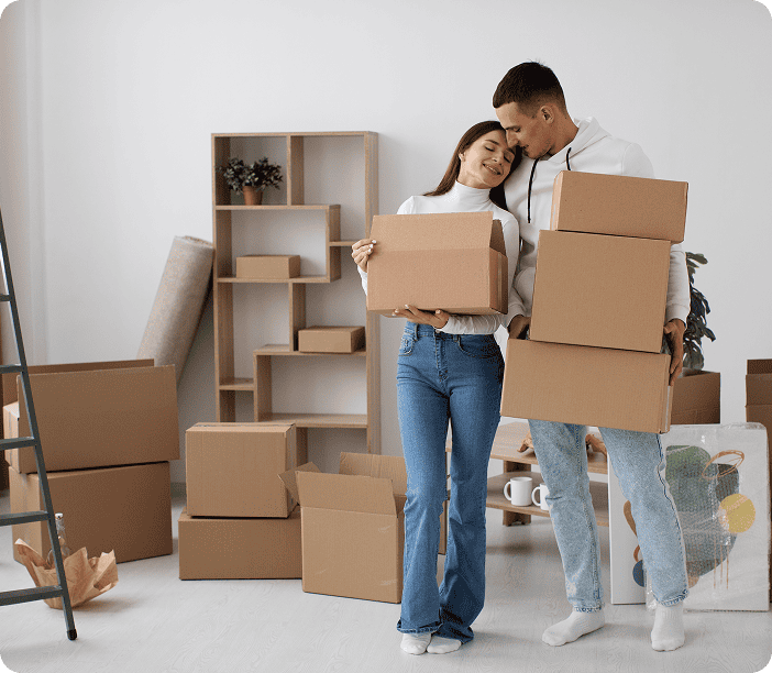 Two people stand in a room holding cardboard boxes, surrounded by more boxes and shelves, capturing a moment of moving or unpacking—just like the reliable experiences shared in brightside trustpilot reviews.